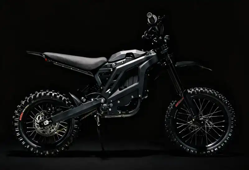 Black dual-sport motorcycle with knobby off-road tires on a dark background, showcasing its matte frame and compact design.